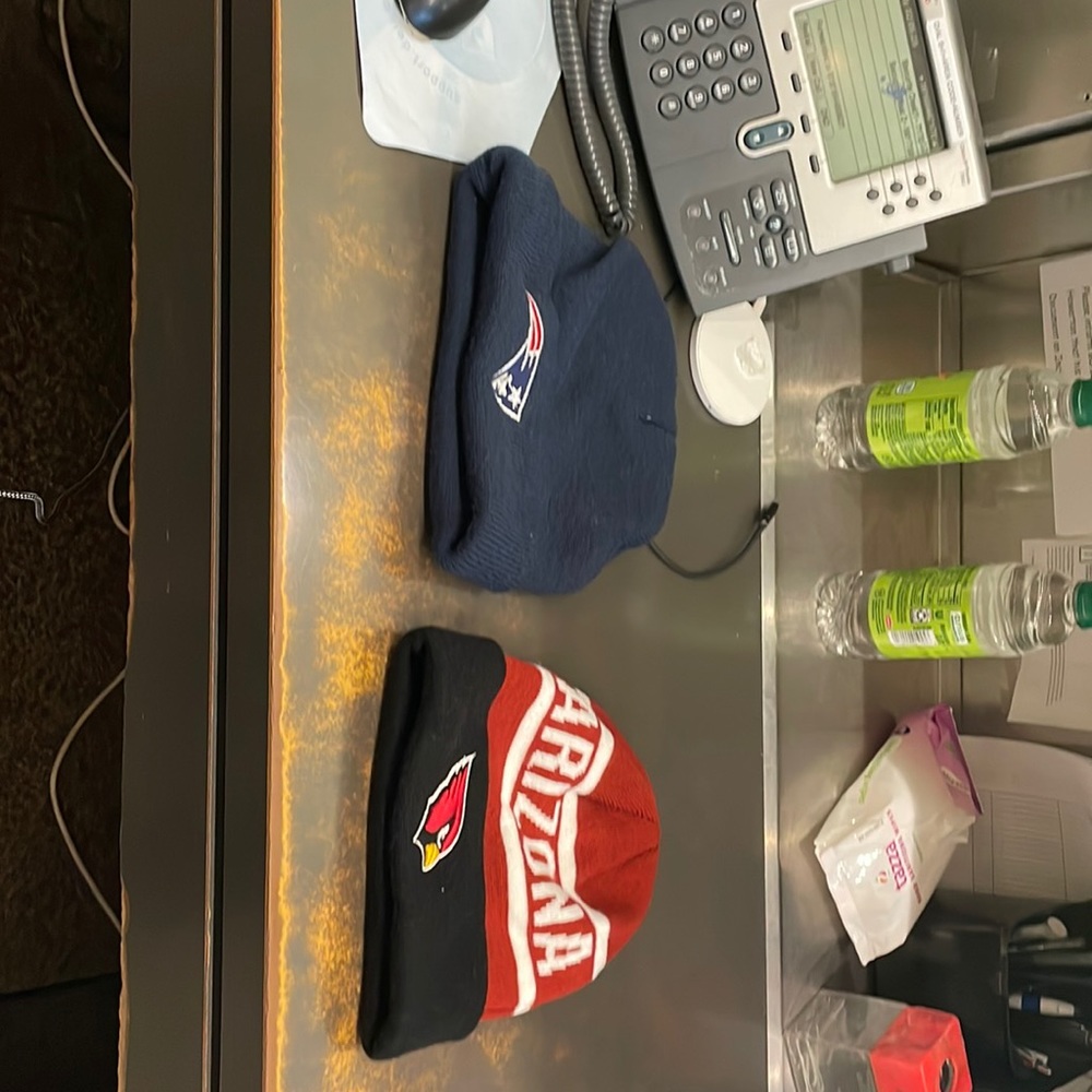 Two men’s stocking caps. One New England Patriots cap and one Arizona Cardinals.